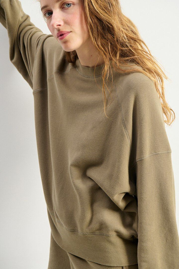 Person wearing a beige sweatshirt on a white background