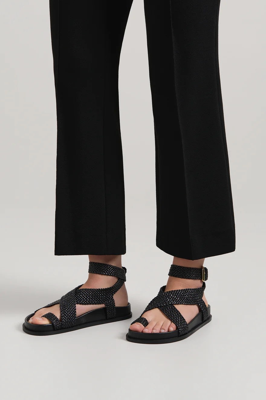 Black sandals worn with black pants on a light gray background