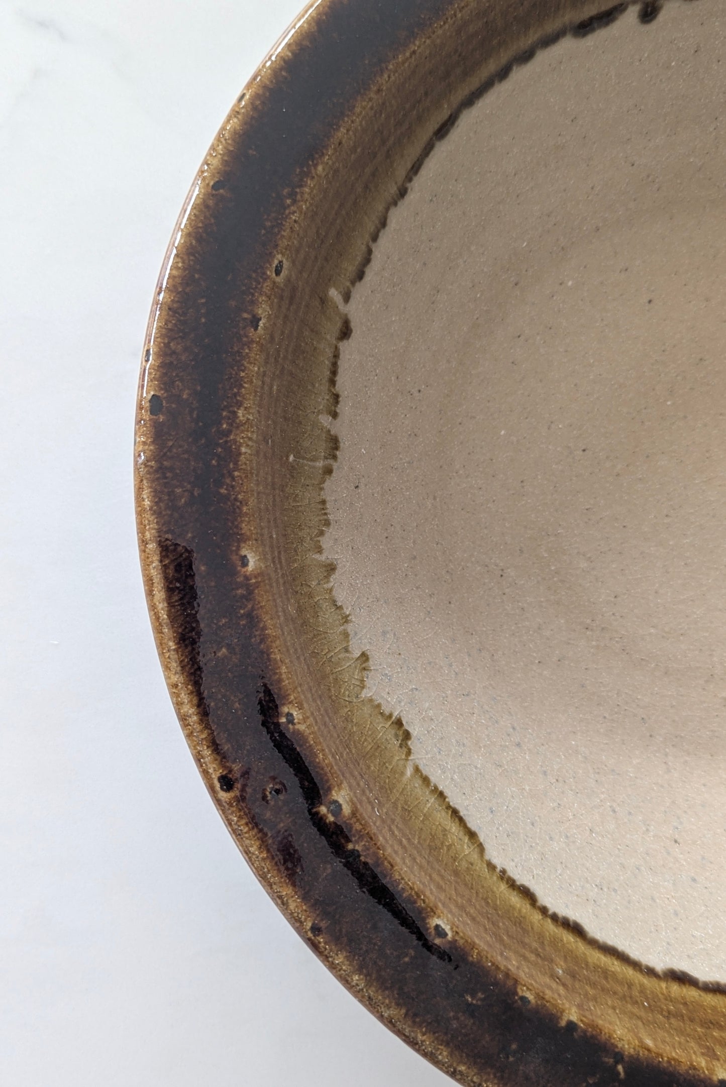 Close-up of a ceramic bowl with a brown rim on a white background