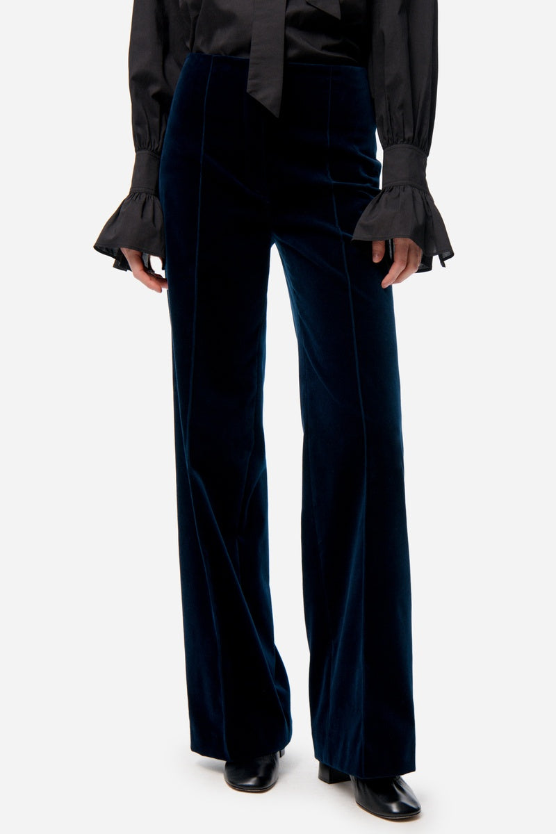Person wearing a black shirt and dark blue velvet pants on a white background