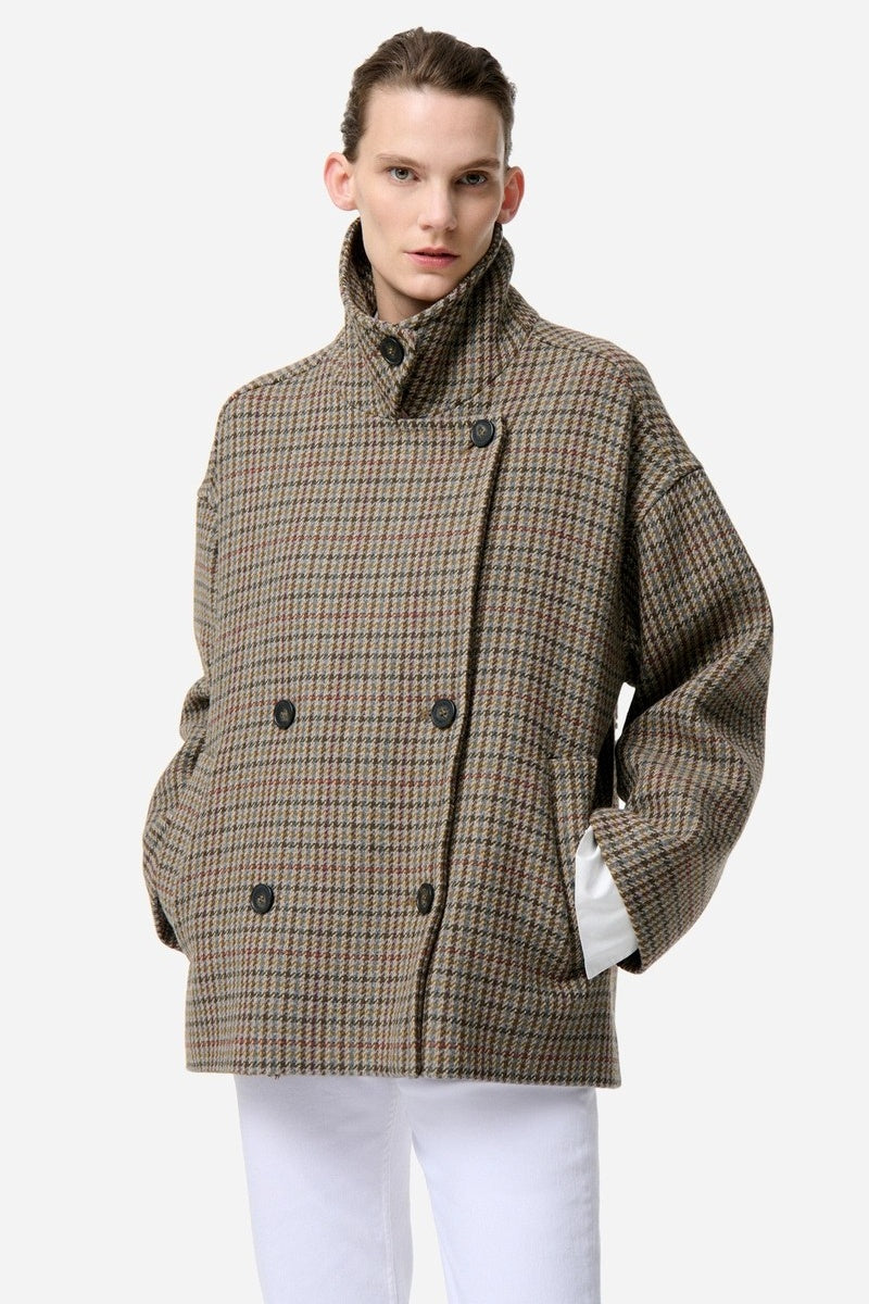 Model wearing a brown checkered Vanessa Bruno coat on a white background
