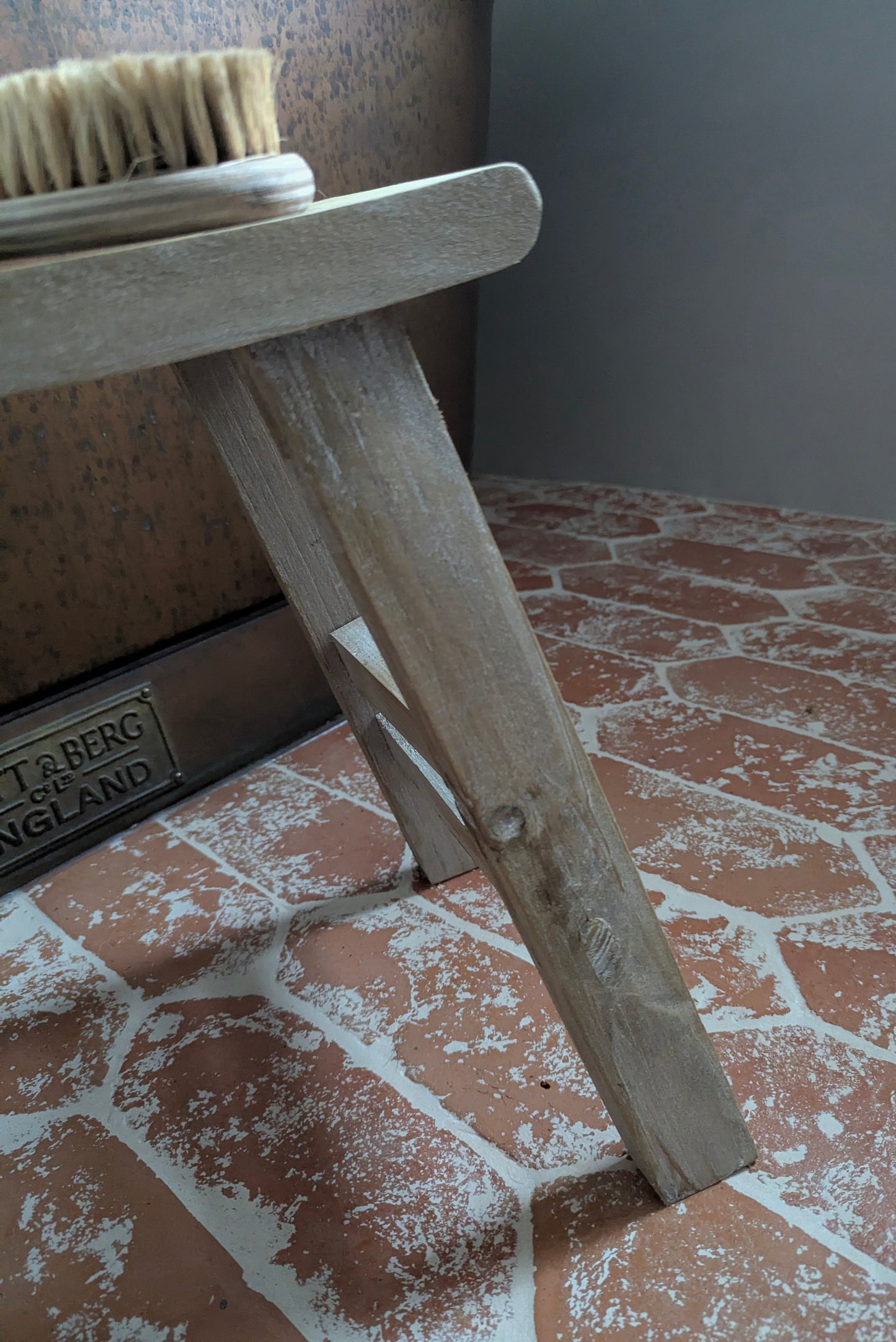 Wooden brush stand with a brush on a tiled floor