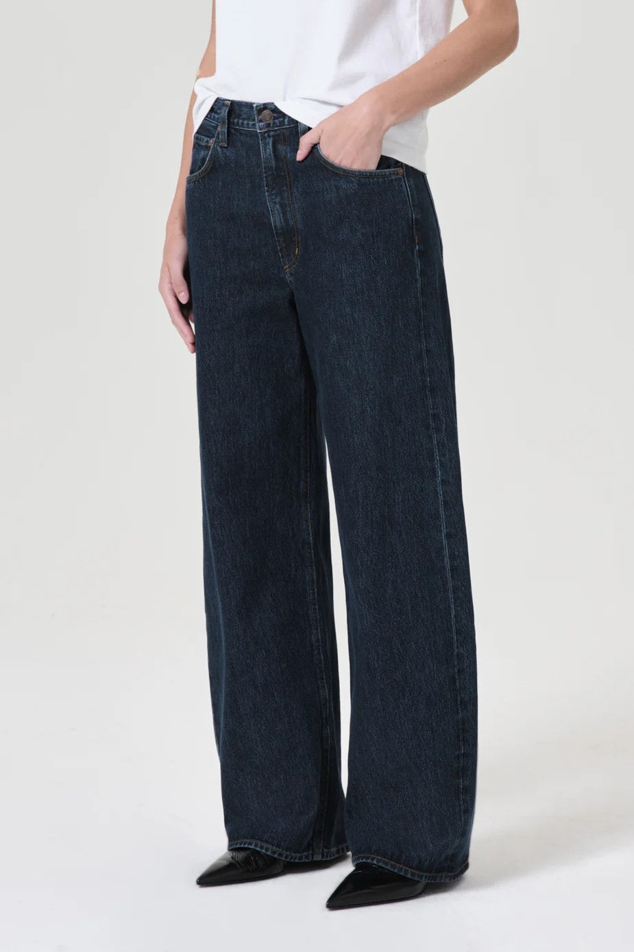 Person wearing dark blue wide-leg jeans on a white background