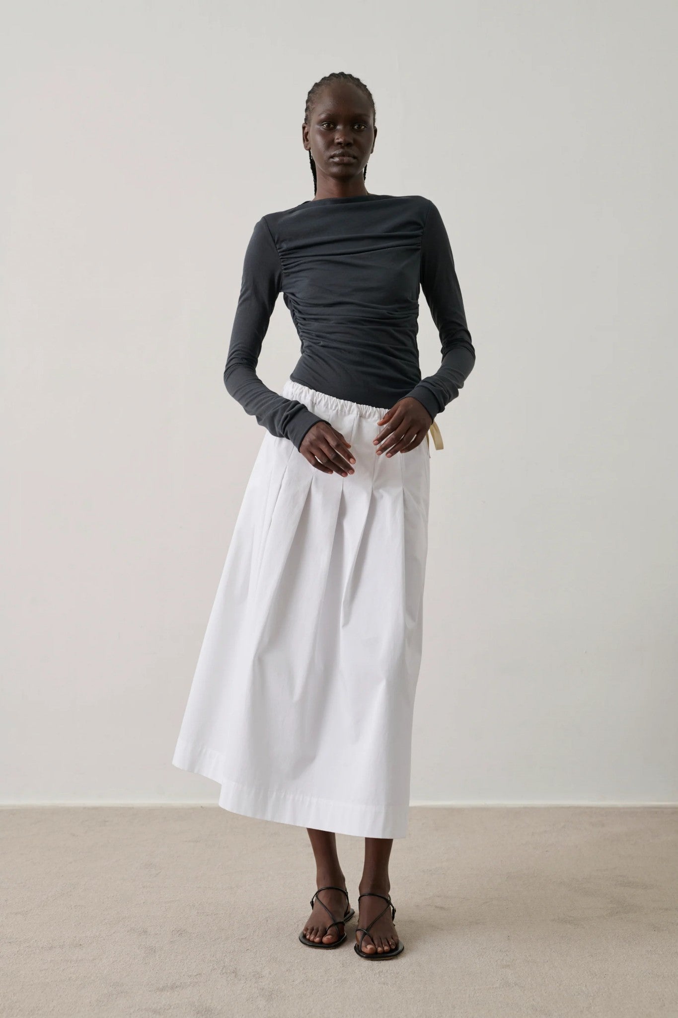 lady in black top and white skirt on pale background