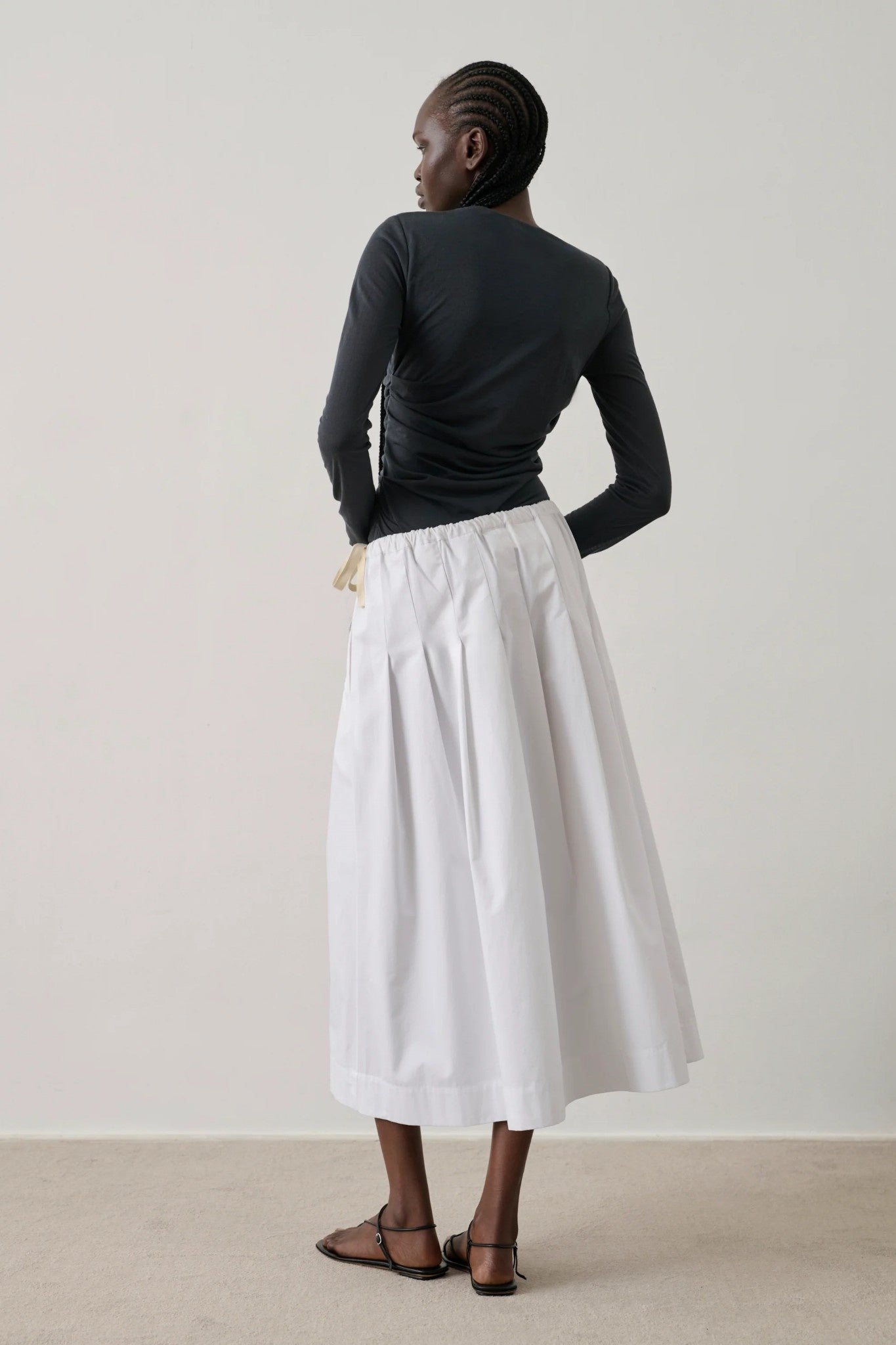 back of lady wearing black top and white skirt