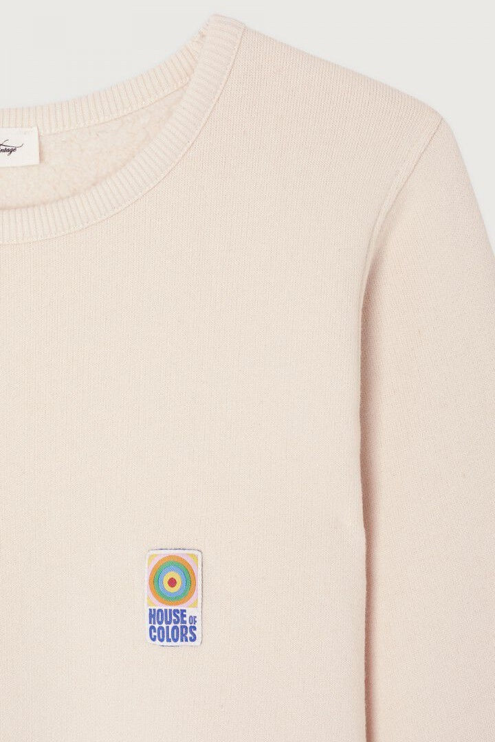 Beige sweater with a colorful patch on a white background