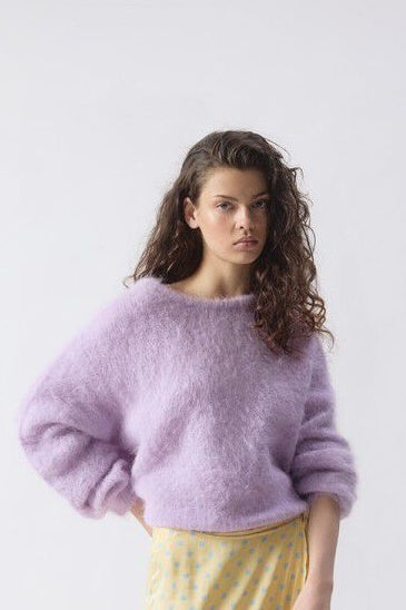 Woman wearing a purple sweater against a plain background