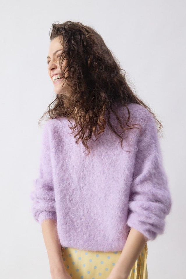 Woman wearing a light purple sweater against a white background