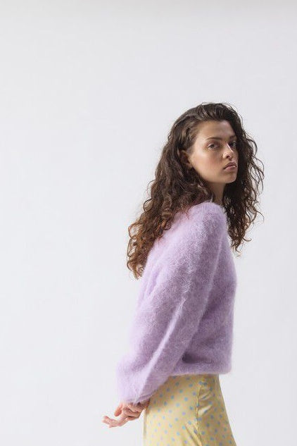 Woman wearing a light purple sweater against a white background