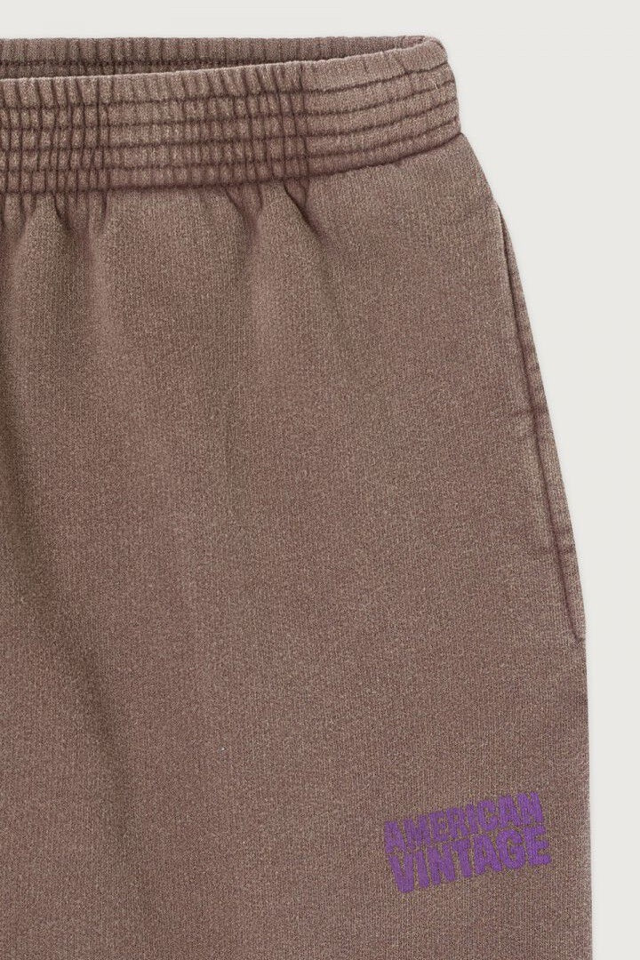 Brown sweatpants with a purple american vintage logo on a light gray background