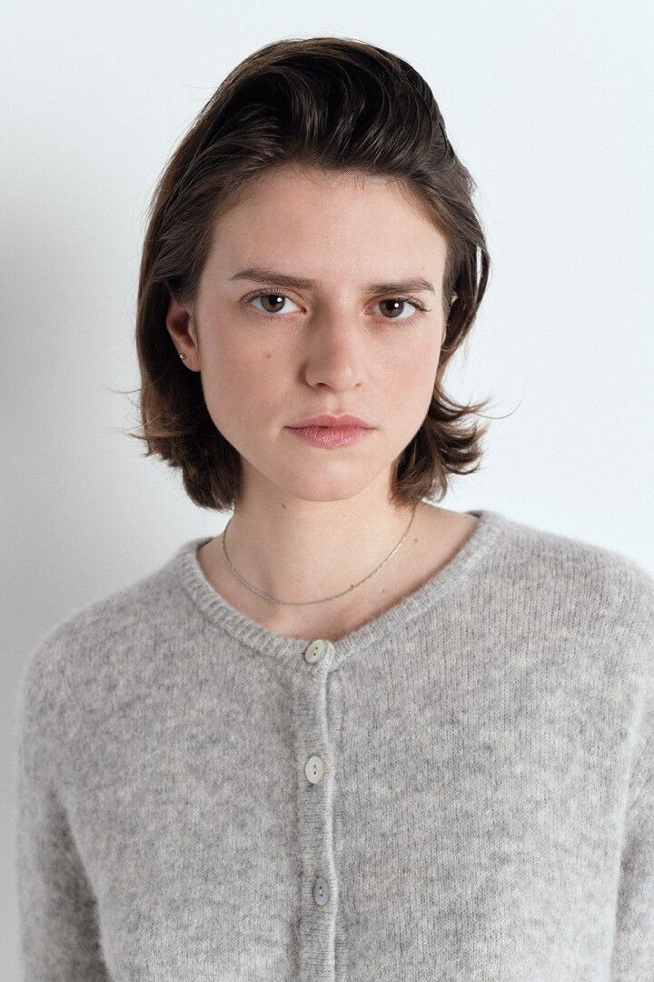Person wearing a grey sweater against a white background