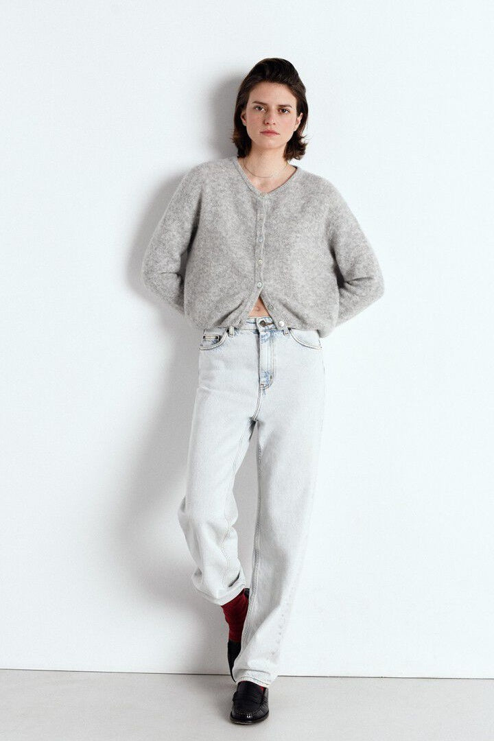 Person wearing a grey cardigan and light blue jeans on a white background