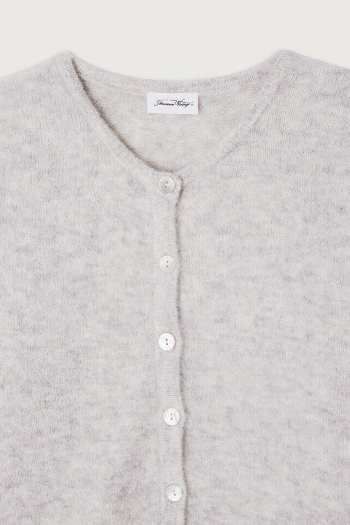 Close-up of a grey cardigan with button details on a light gray background
