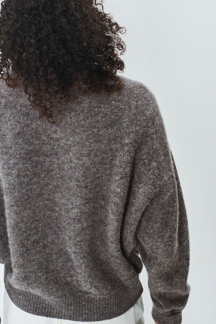 Person wearing a grey sweater from behind on a white background