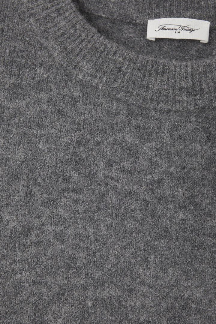 Gray sweater with a brand label on a grey background