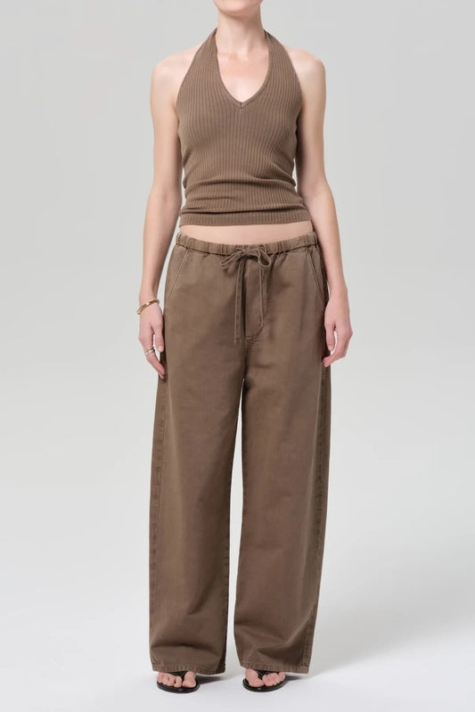 A model wearing a brown ribbed halter crop top and matching wide-leg drawstring pants, photographed against a light gray studio background.