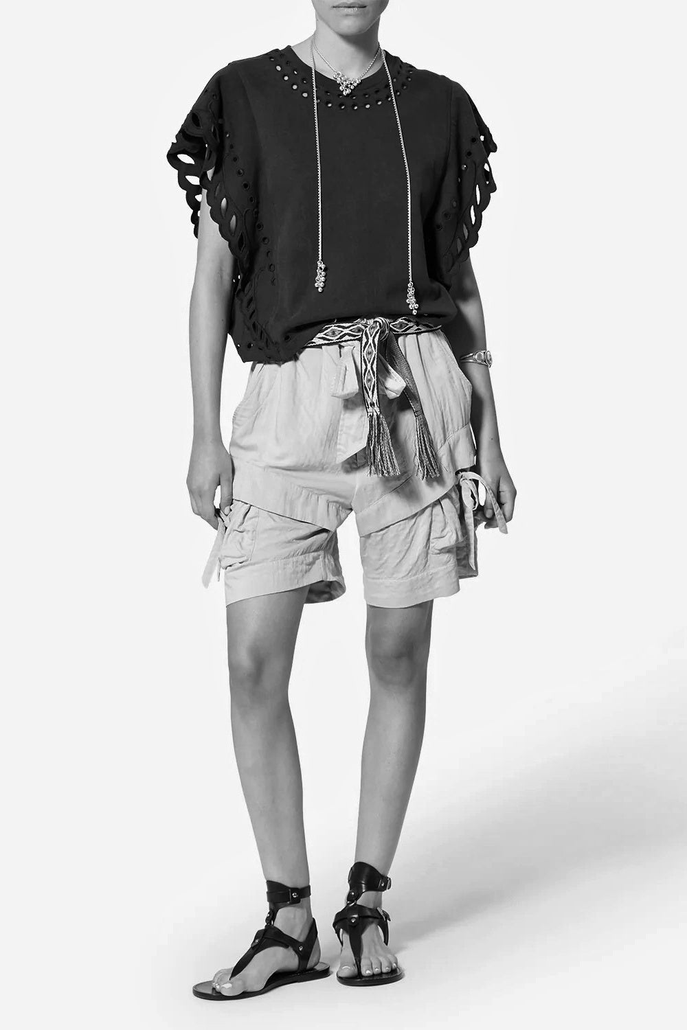 Person wearing a black top with ruffled sleeves and Bermia shorts on a white background