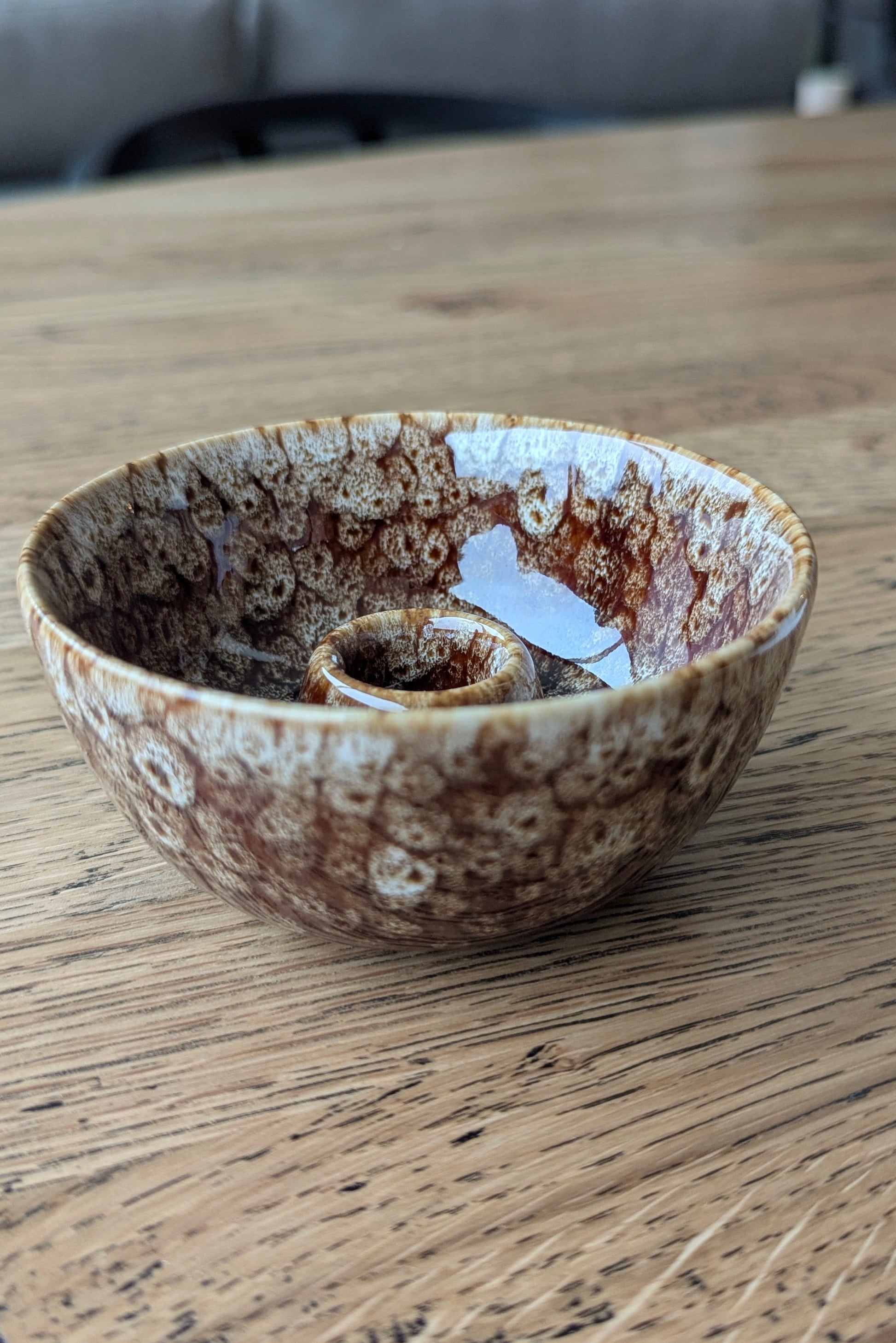 Ceramic bowl with speckled brown and beige design on a wooden surface