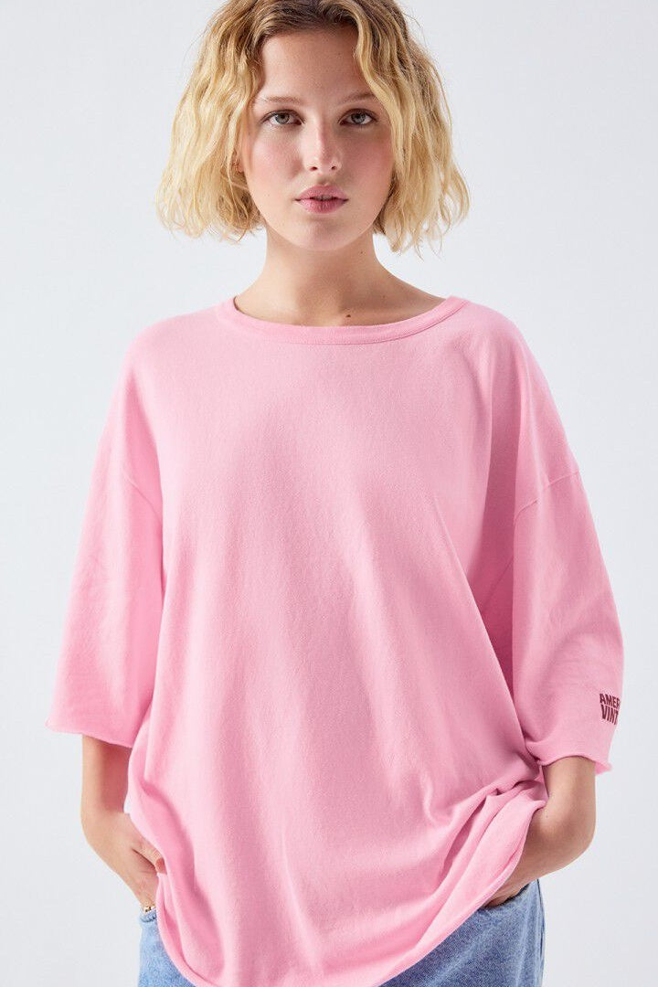 Woman wearing a pink oversized shirt against a light gray background