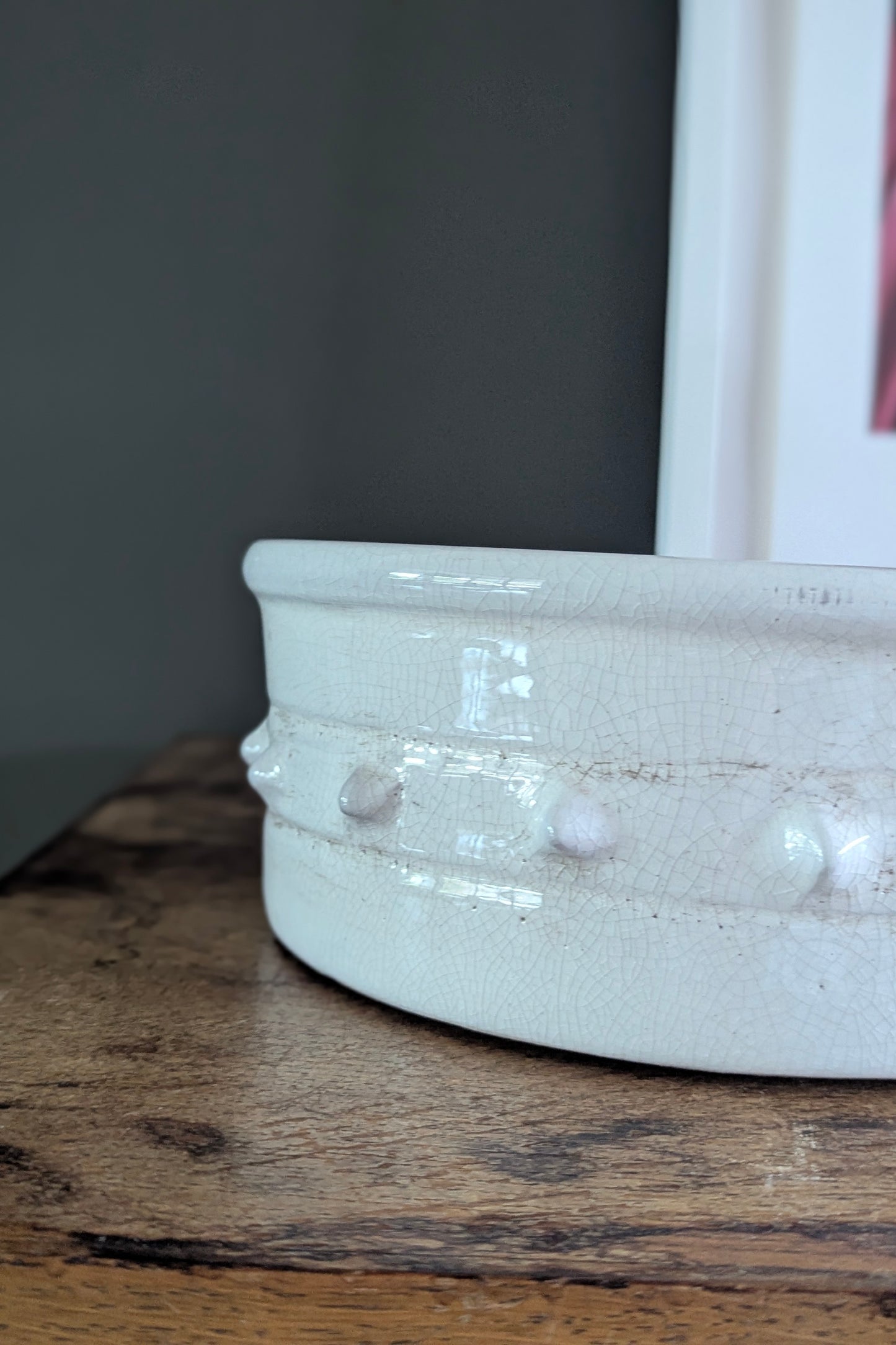 Close-up of a white ceramic bowl with decorative elements on a wooden surface.
