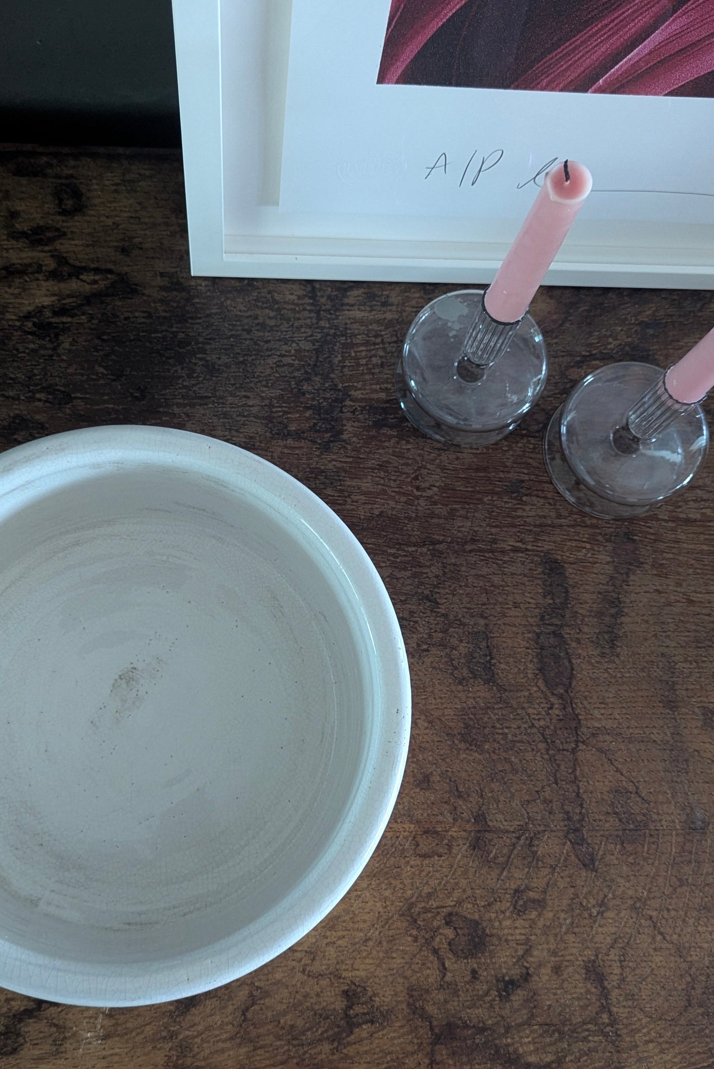 Two candle holders on a wooden surface next to a white bowl.
