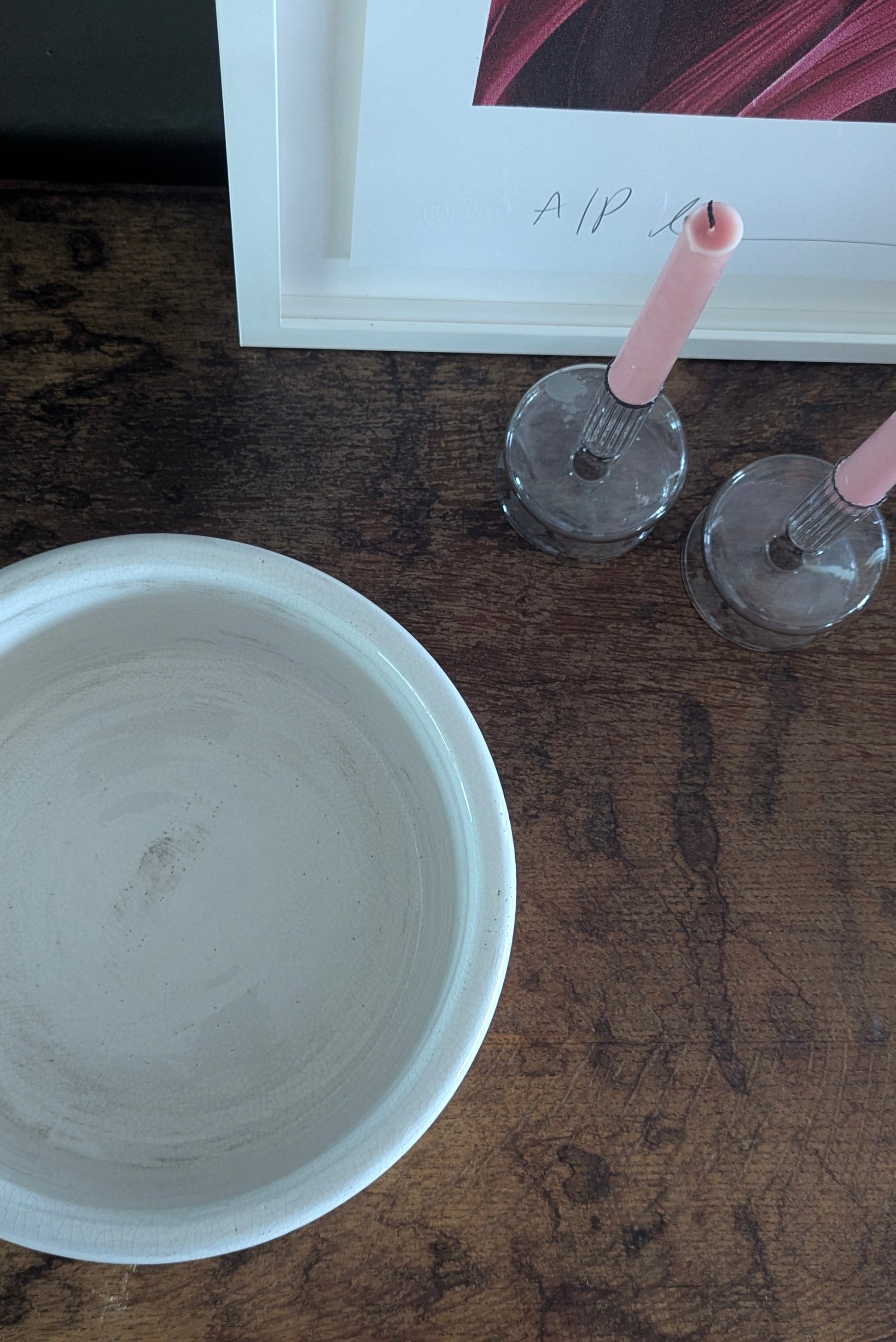 Two candle holders on a wooden surface next to a white bowl.