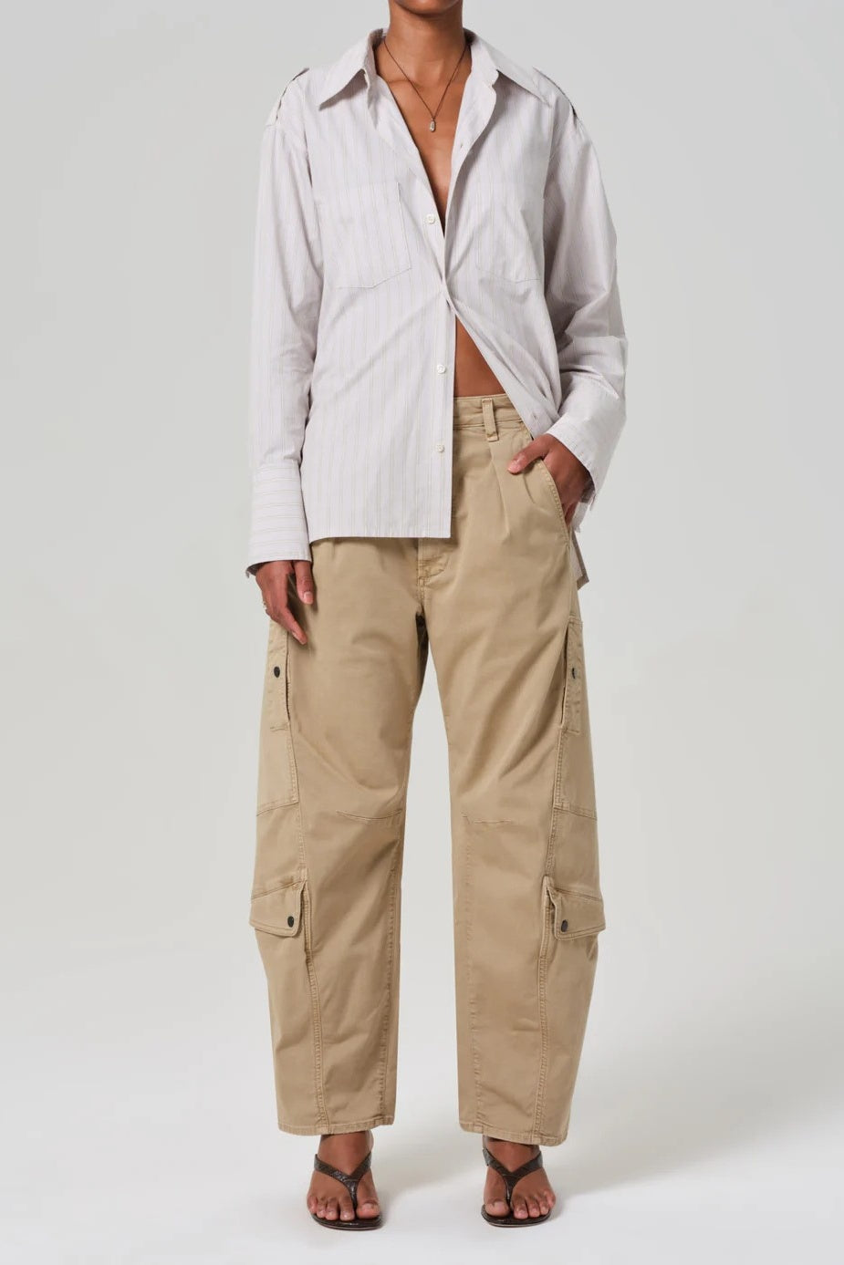 Person wearing a light-colored shirt and beige cargo pants on a white background