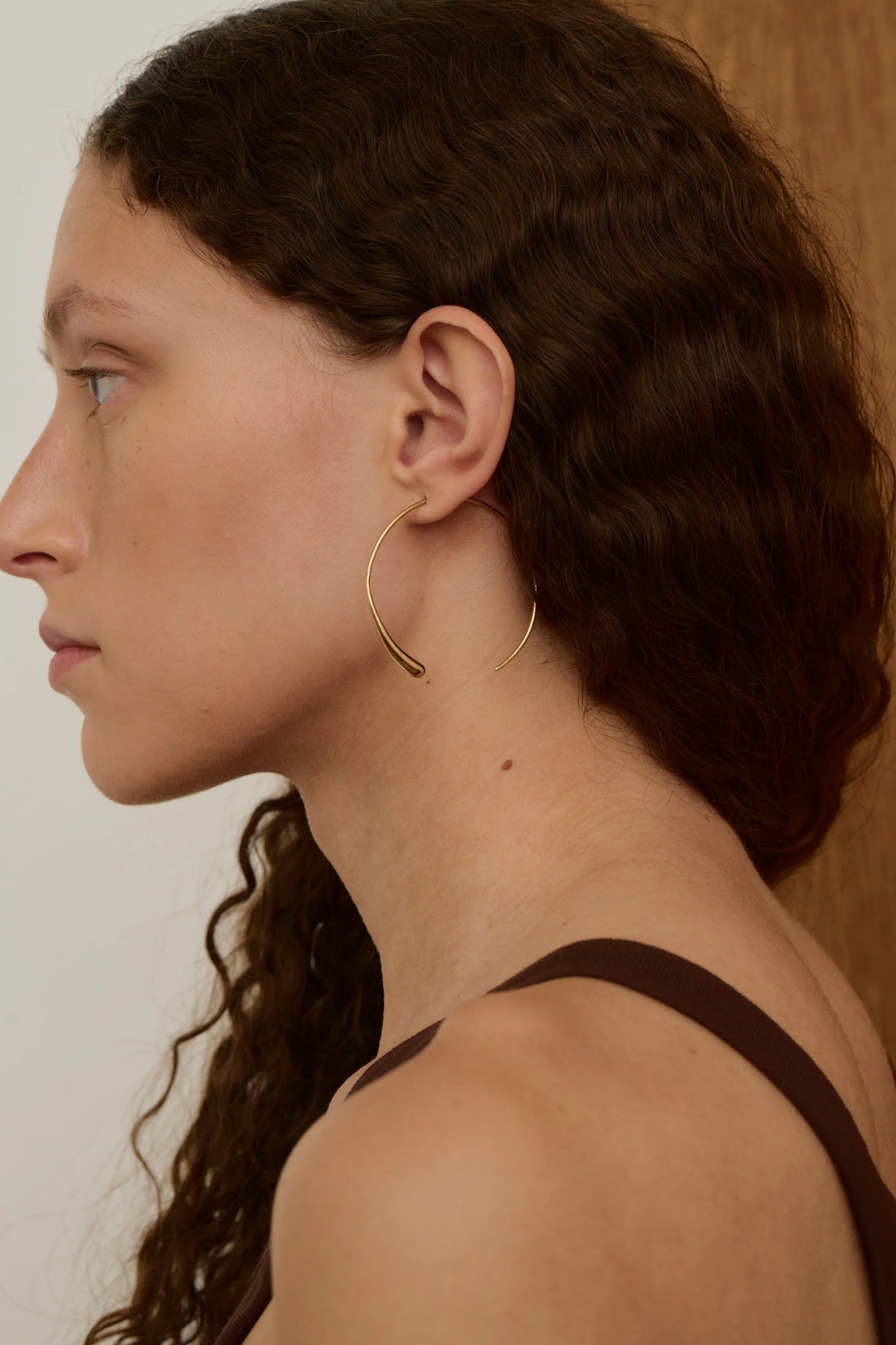 Woman wearing gold hoop earrings with a neutral background