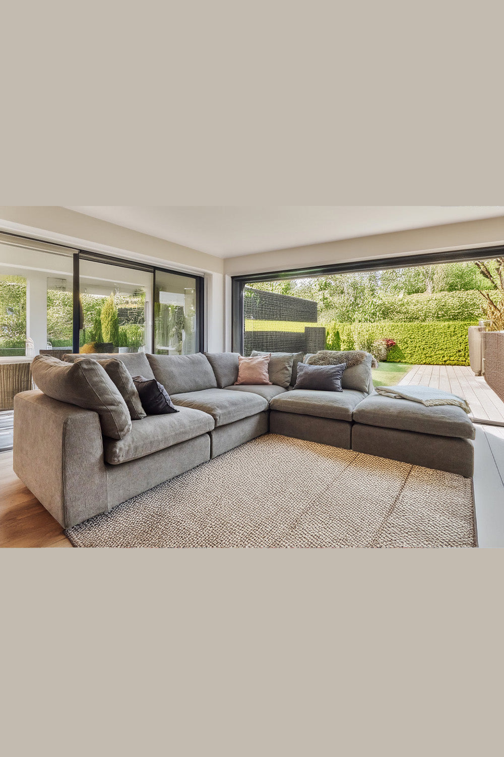 Grey sectional sofa in a modern living room with large windows.