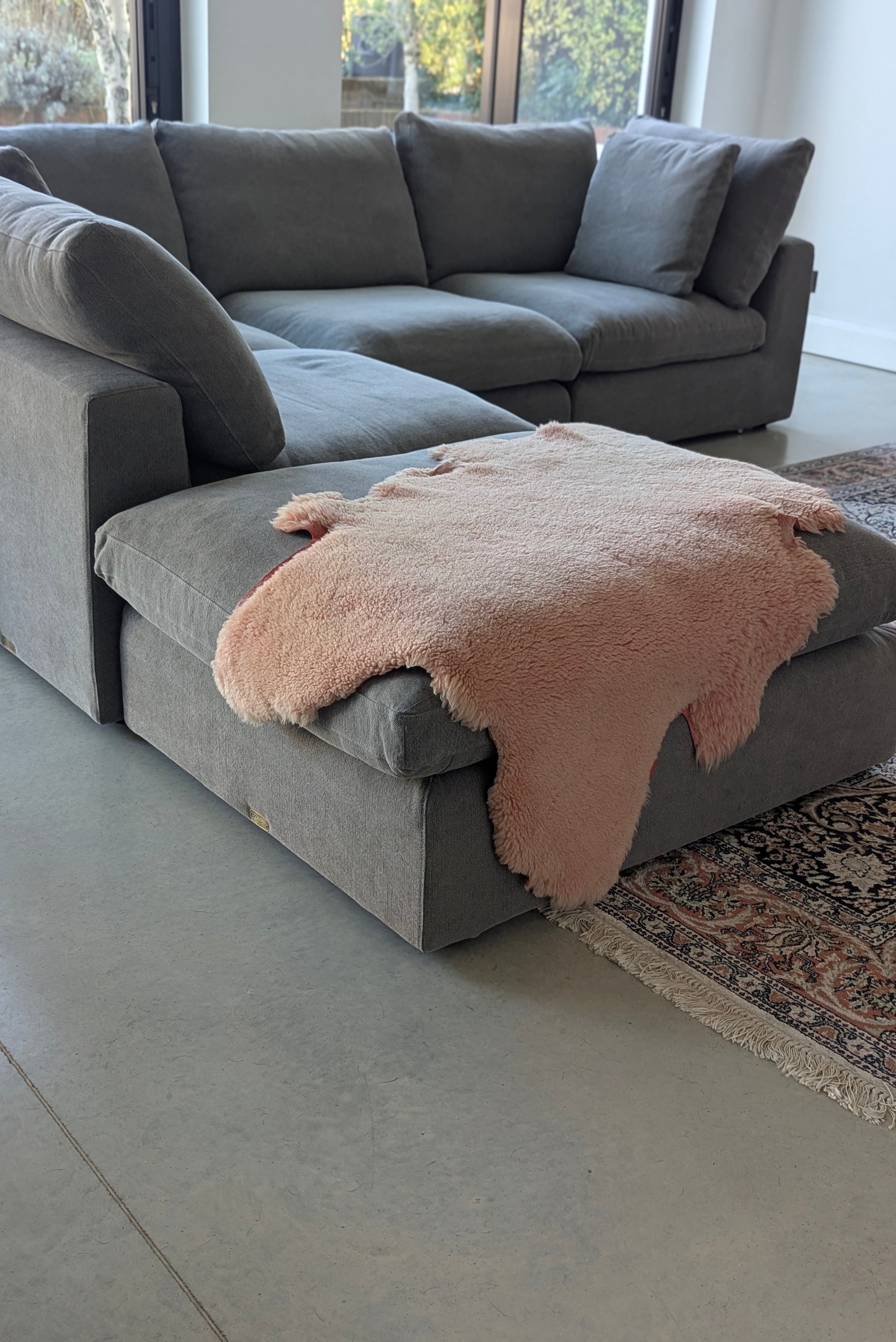 Gray sectional sofa with a pink blanket in a living room setting