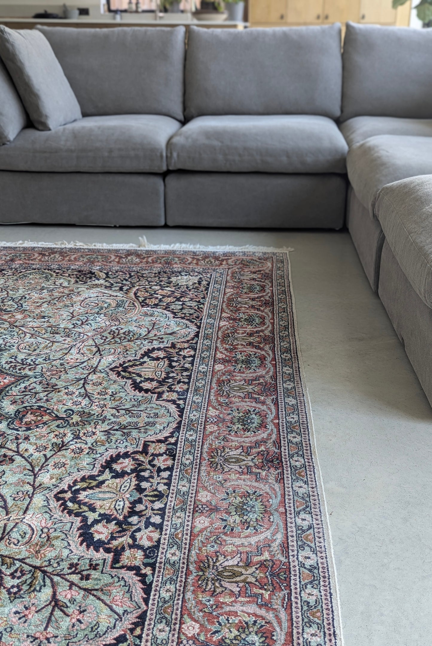 Grey sectional sofa with a patterned rug in a living room setting