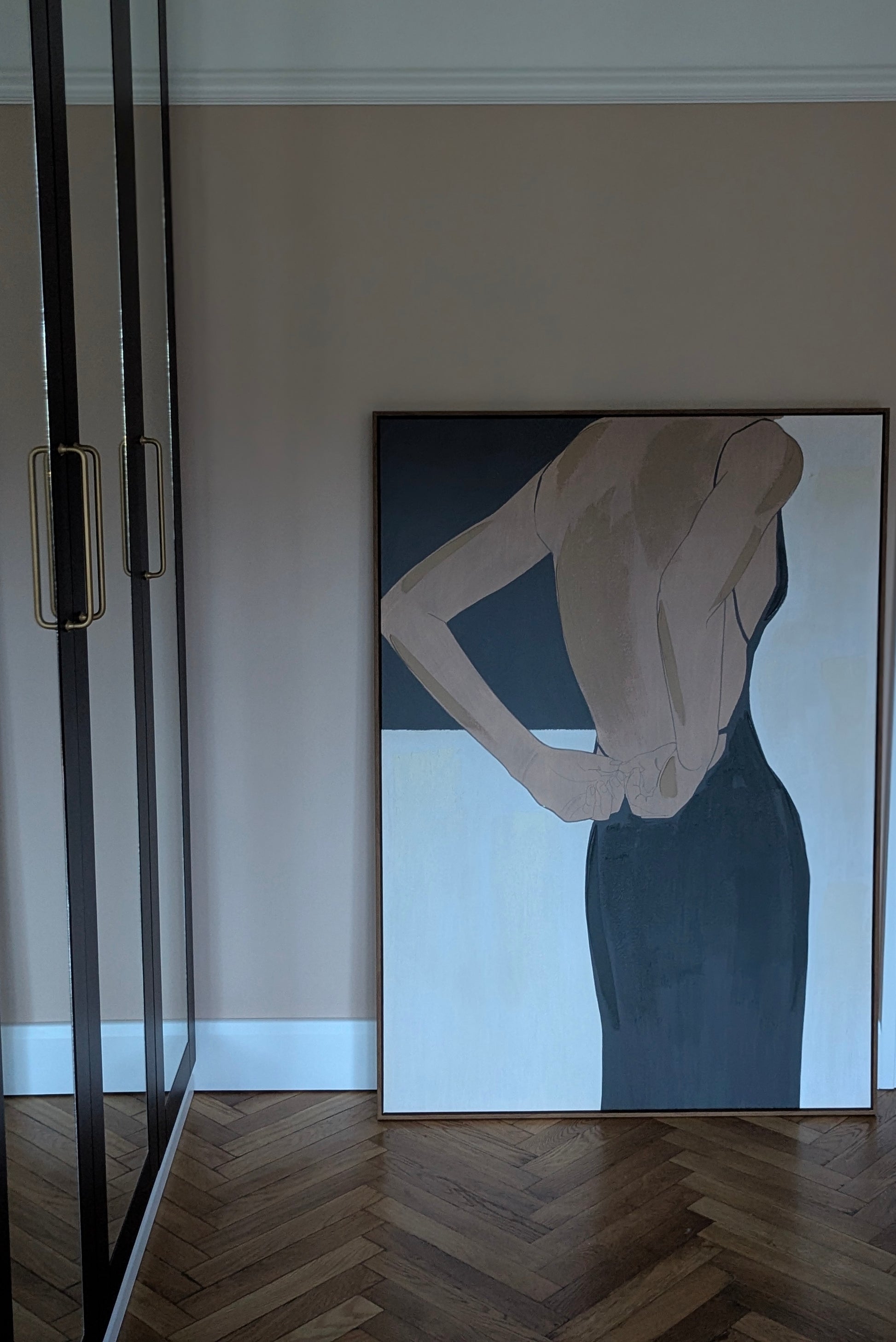 Abstract painting of a woman in a dark dress on a wall in a room with wooden flooring.