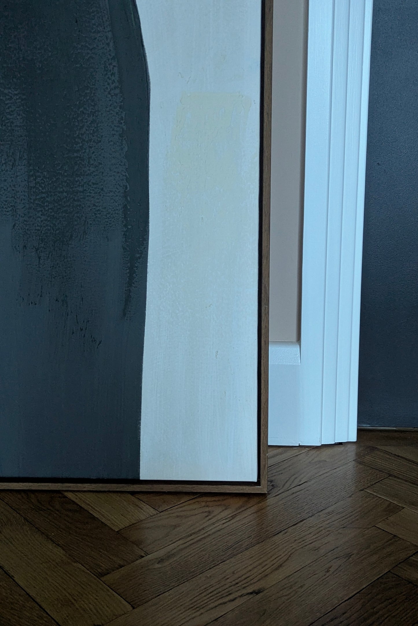 Close-up of a framed painting on a wall with a wooden floor.