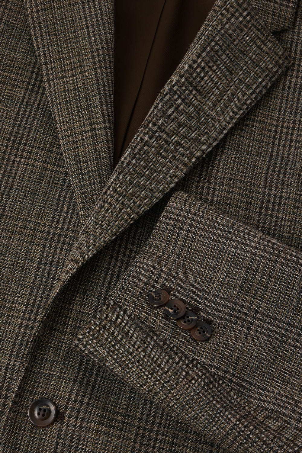 Close-up of a brown checkered suit jacket with a button.