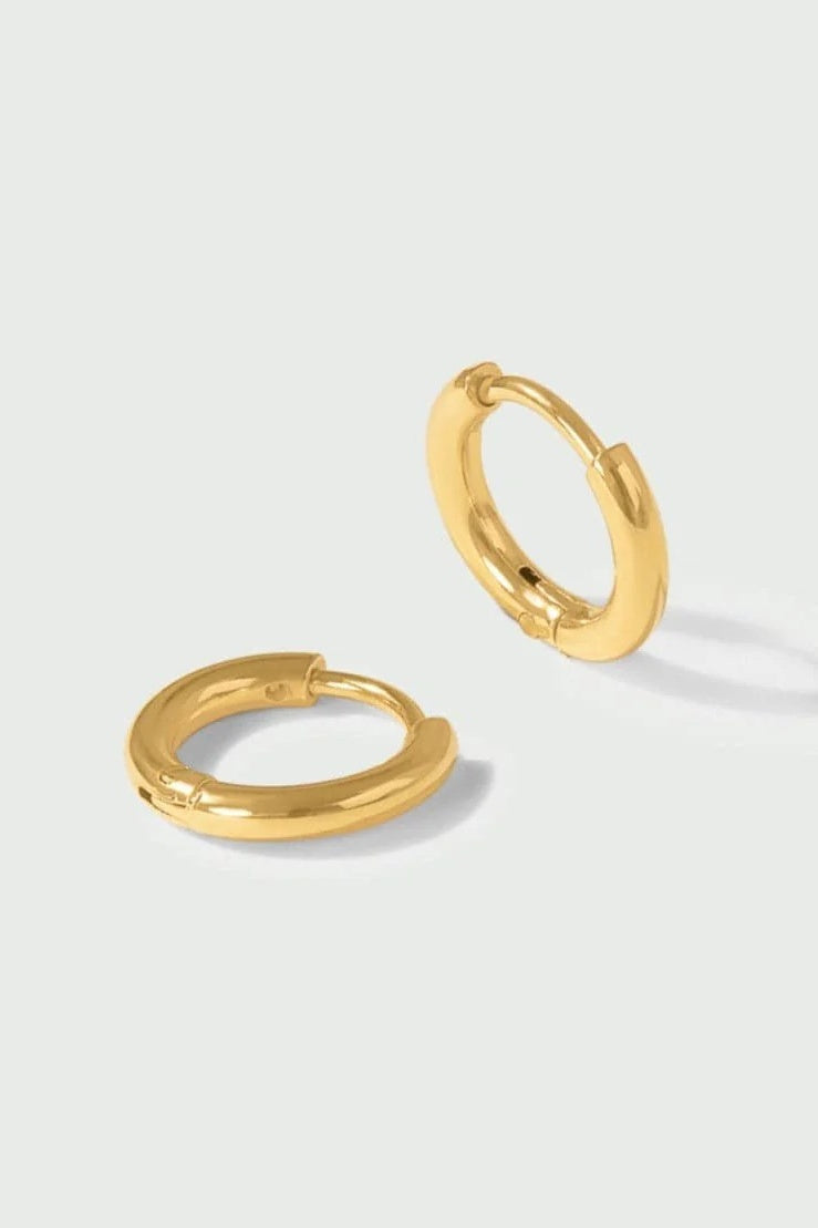 gold huggie earrings on white background