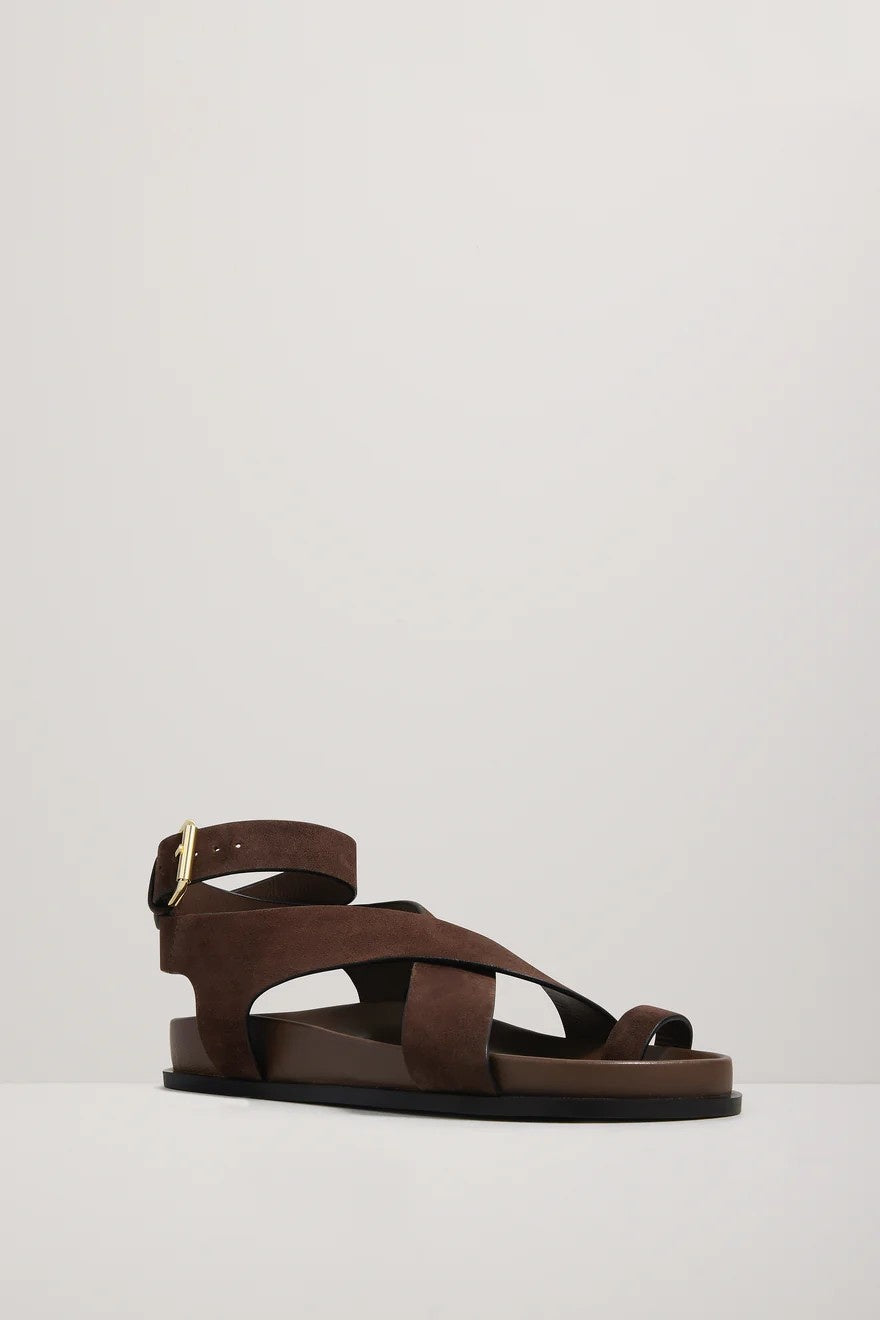 Brown sandal with criss-cross straps on a light gray background