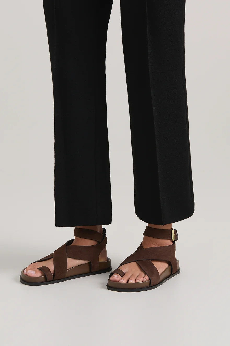Brown sandals worn with black pants on a light gray background