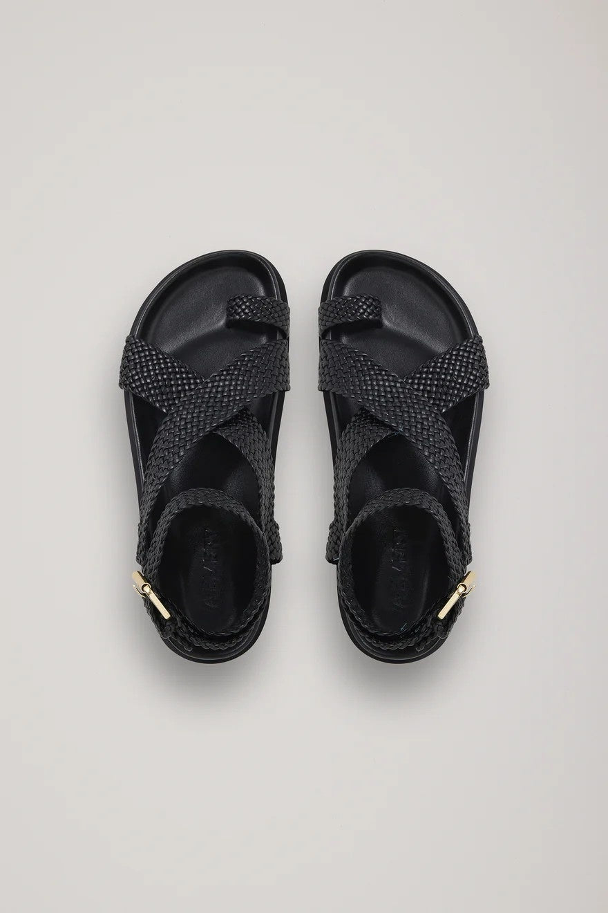 Pair of black sandals with gold accents on a light gray background