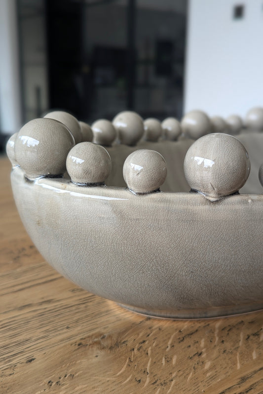 Ceramic bowl with spherical protrusions on a wooden surface