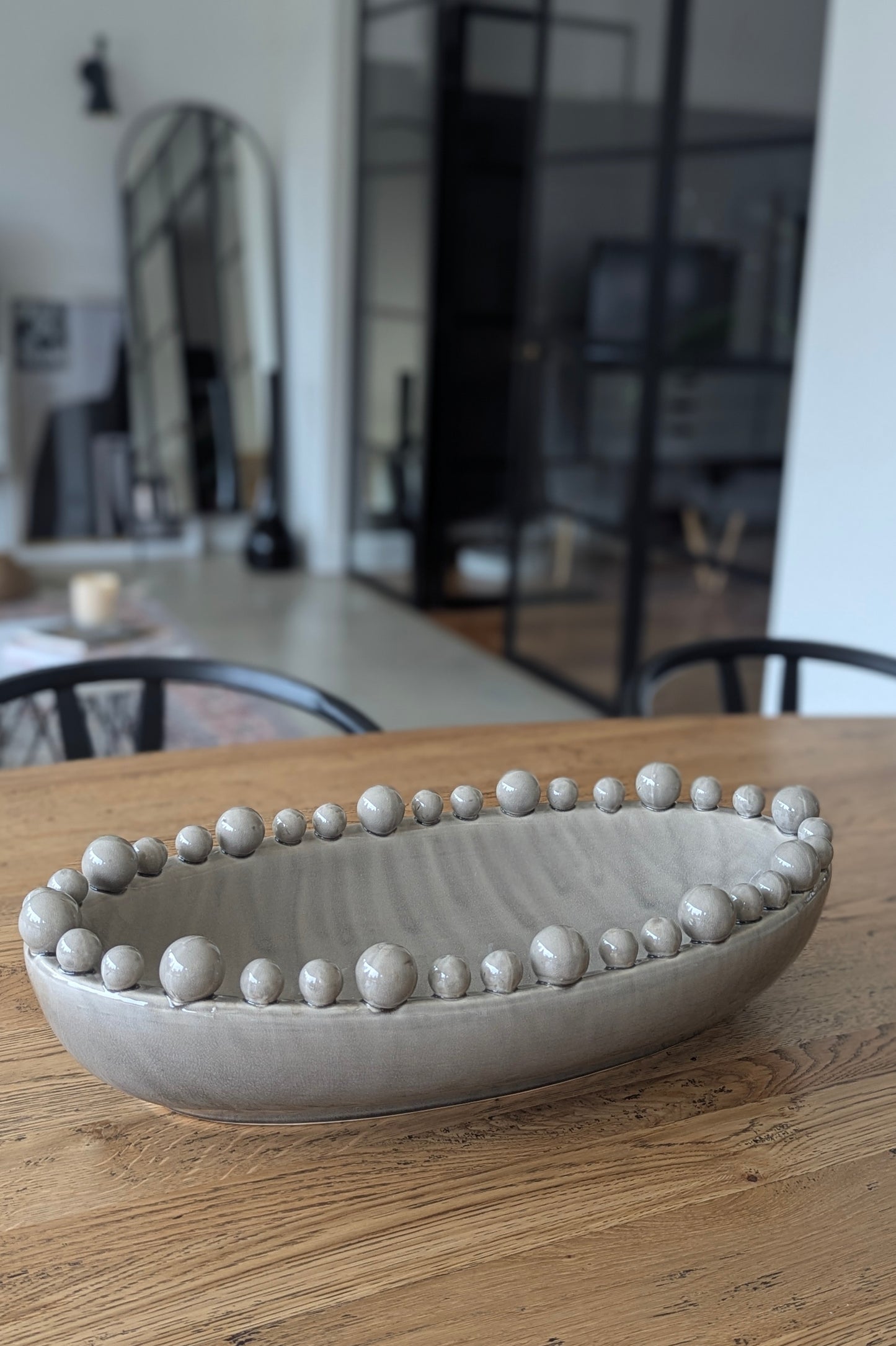 Decorative ceramic bowl with bead-like embellishments on a wooden surface.