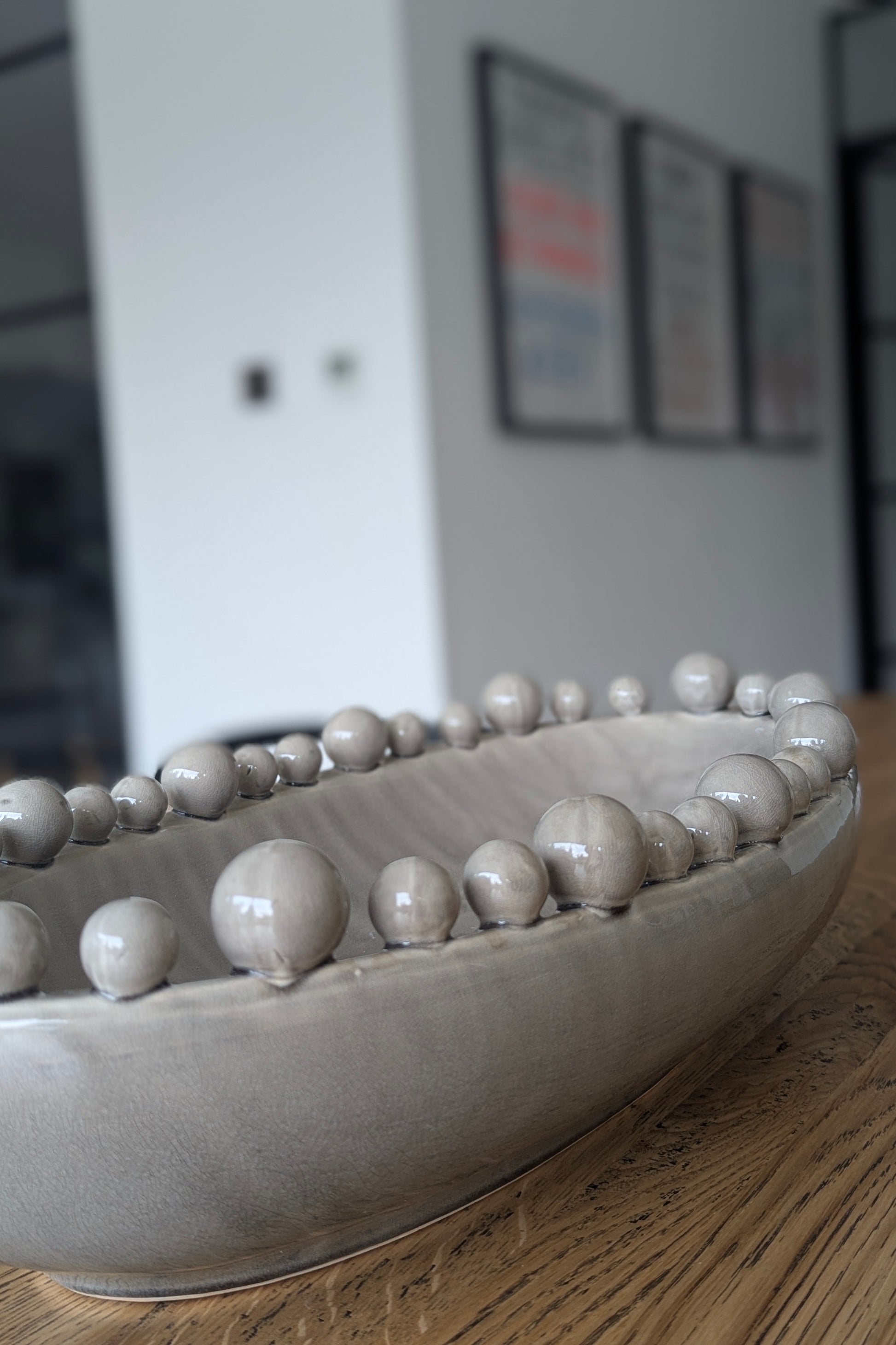 Grey ceramic bowl with spherical decorations on a wooden surface