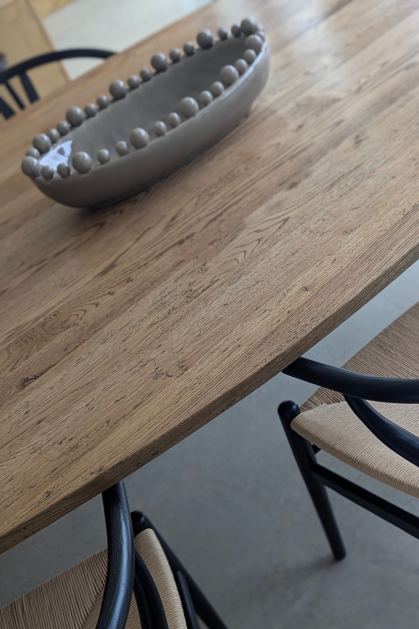 Grey decorative bowl on a wooden table with chairs around it