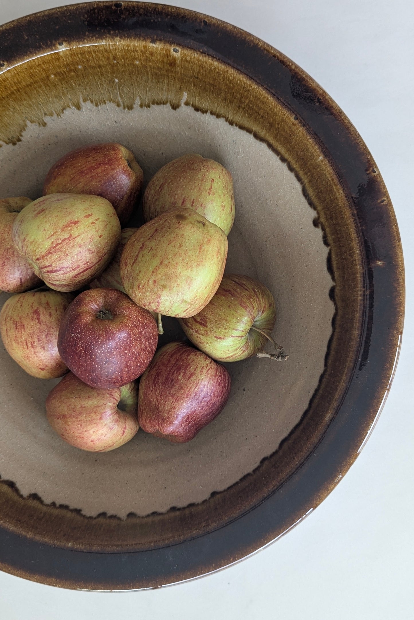 Apples in a terracotta bowl on a white background