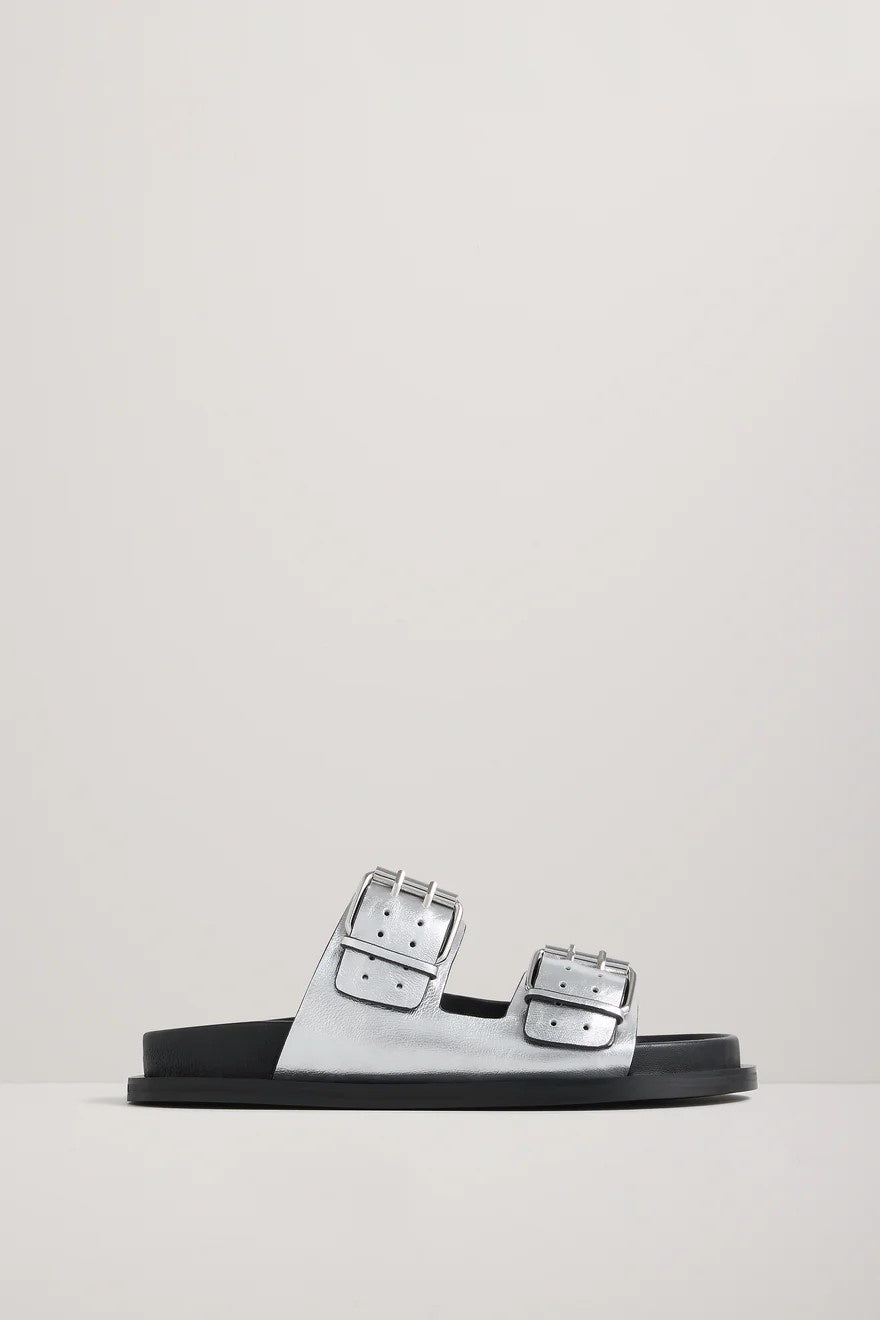 Silver sandal with silver buckles on a light gray background