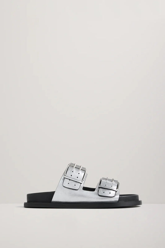 Silver sandal with silver buckles on a light gray background