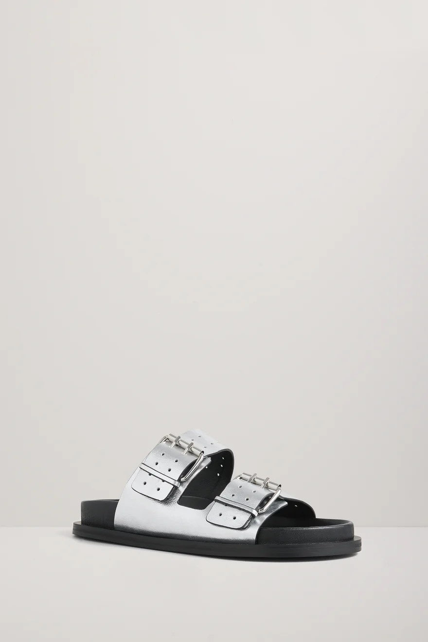 Silver sandal with black soles and silver buckles on a light gray background