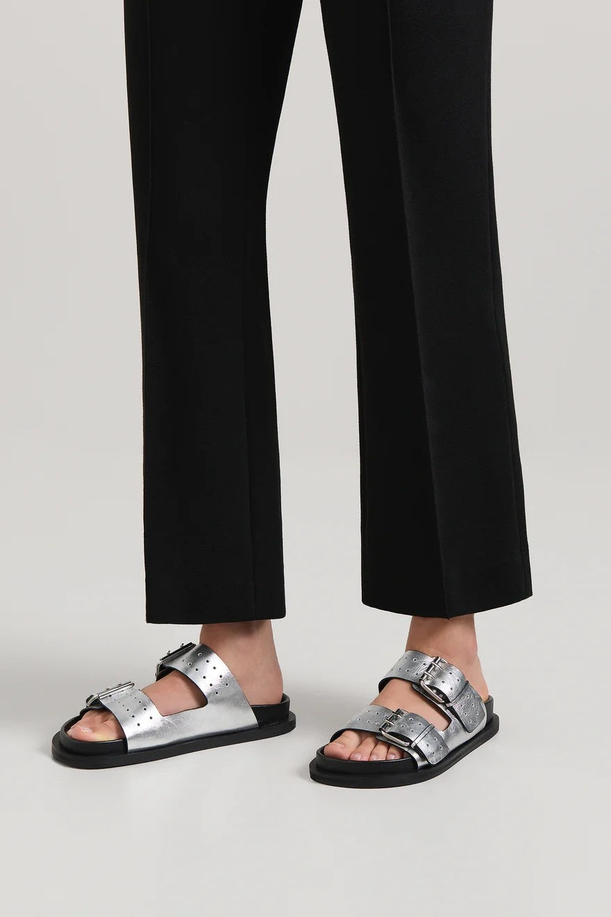 Silver sandals worn with black pants on a light gray background
