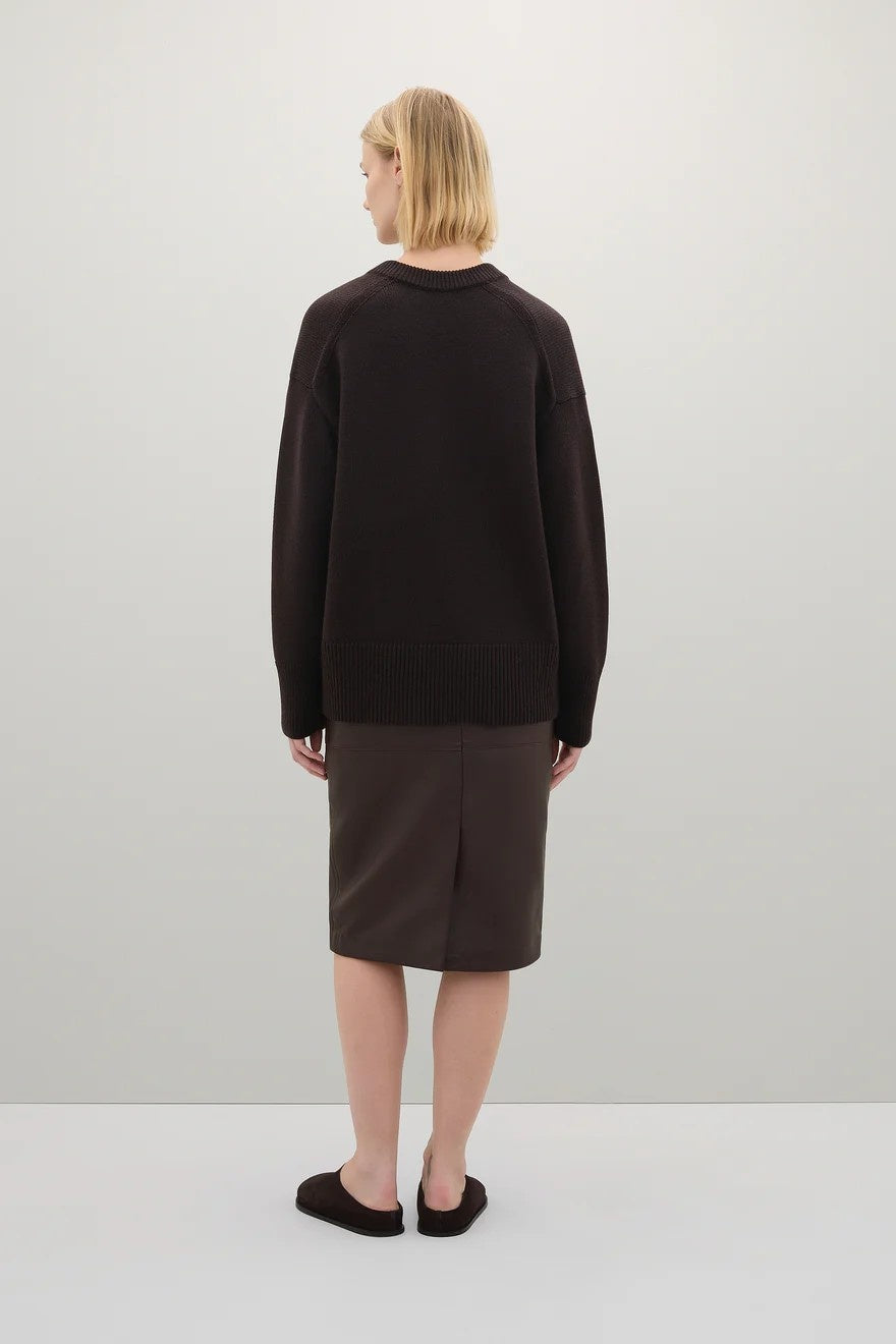 Person wearing a brown sweater and brown skirt on a white background