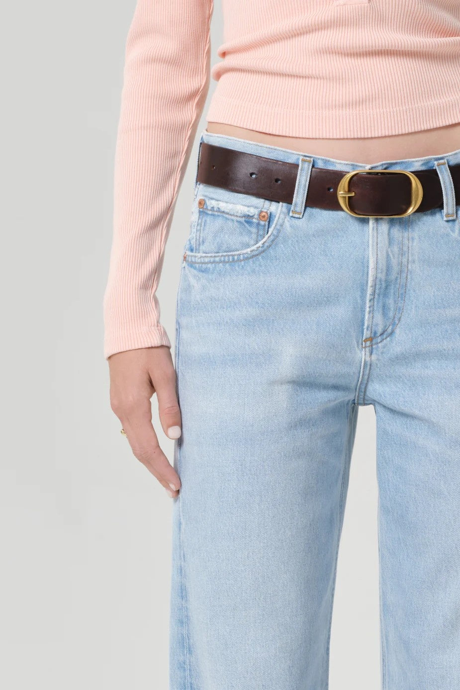 mis section image of girl in peach top, brown belt and pale blue jeans 