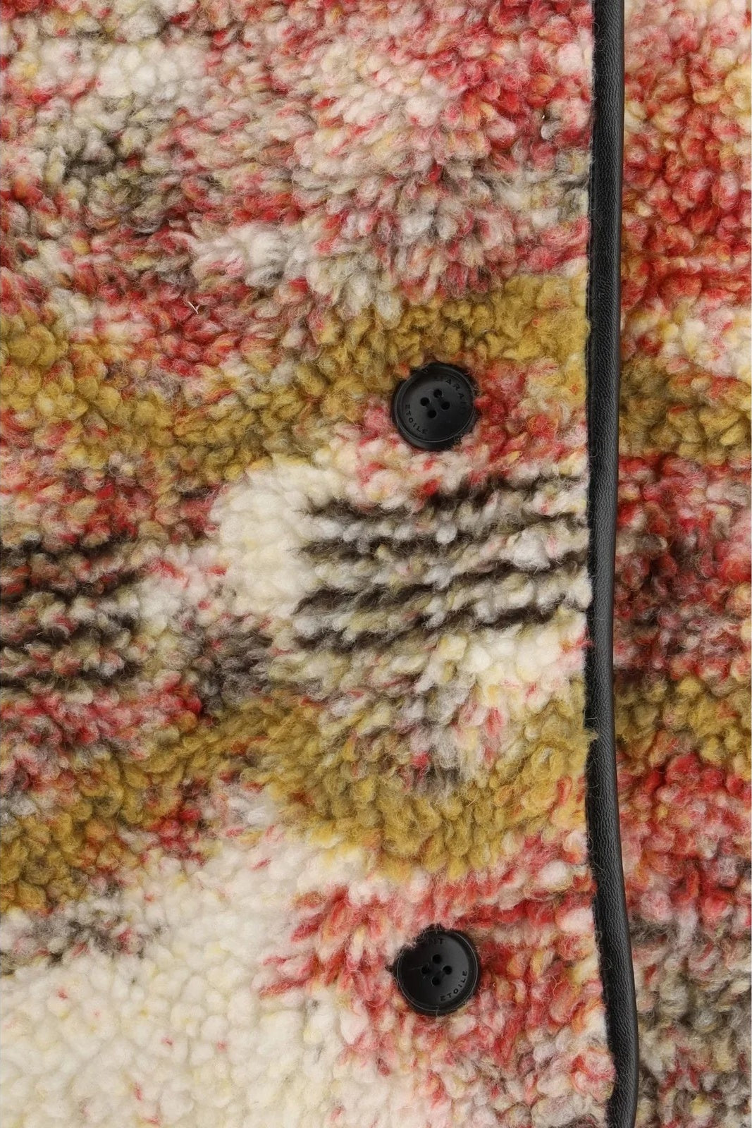 Close-up of a textured fabric with colorful patterns and black buttons.